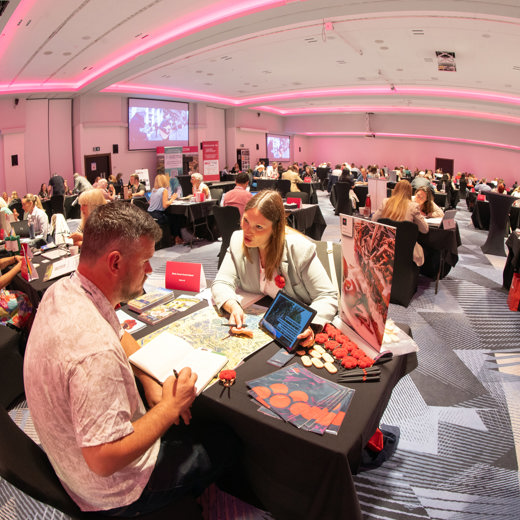 A room full of people at 1 to 1 meetings across desks