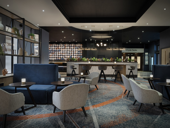 Large hotel lobby with various tables, chairs and couches.