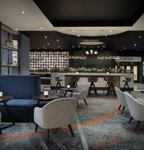 Large hotel lobby with various tables, chairs and couches.