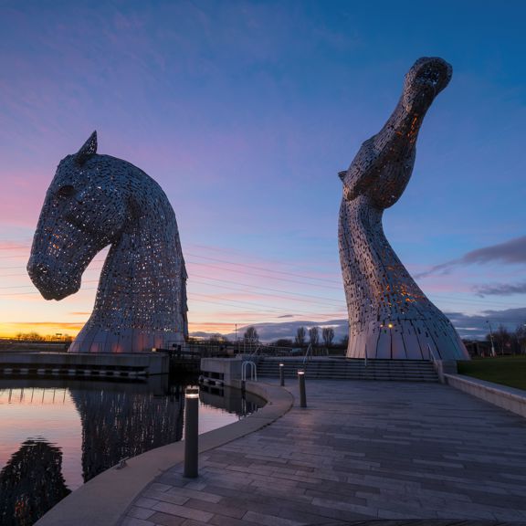 Two giant metal kelpie head sculptures at dusk