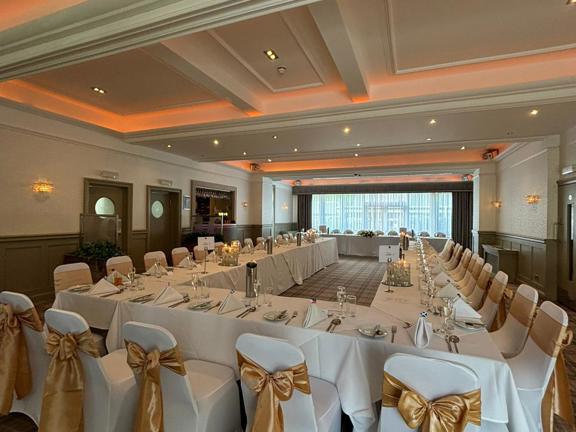 Hotel function with tables and chairs set up in a u-shape. 