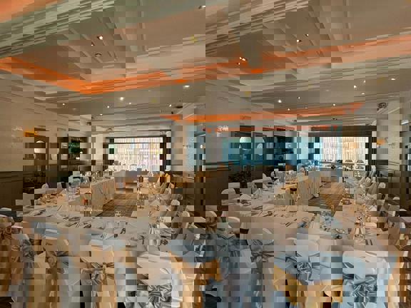 Hotel function with tables and chairs set up in a u-shape. 