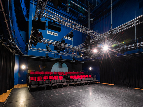 Theatre room with rigged lighting and tiered seating.
