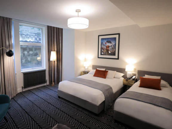 Light and modern hotel bedroom with two double beds and a large window