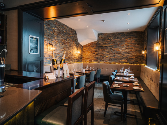 Cosy hotel bar with stone wall and wooden tables and leather chairs. 