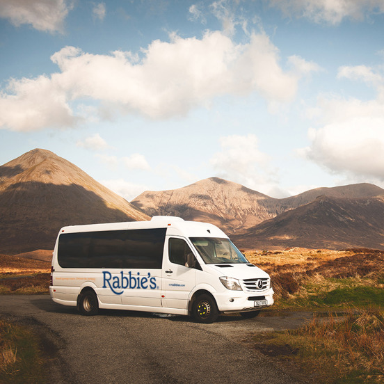 Rabbie's mini coach parked in front of hills