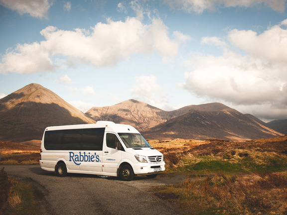 Rabbie's mini coach parked in front of hills