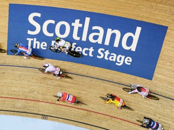 Group of cyclists on a track with a 'Scotland The Perfect Stage' sign.