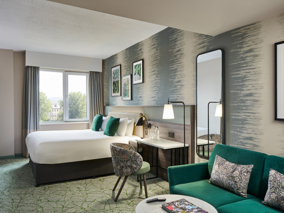 Large family room with double bed and sofa bed. Accents of green in the soft furnishings. 
