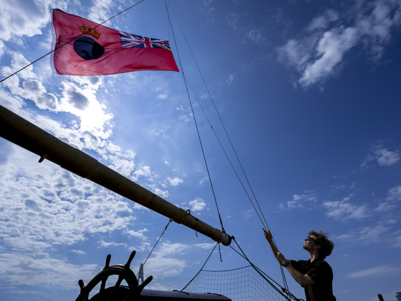 Person raising a flag on a tall ship