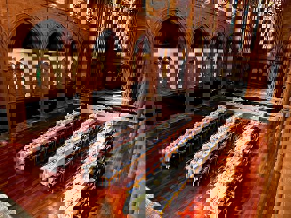 The Grand Hall at The Barony set up with three long tables running the length of the room. Another long table runs across the top of the room from left to right.  All are covered with white table linen and flowers.