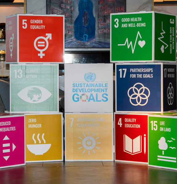 10 large paper cubes piled in a pyramid shape, with one of the UN Sustainable Development Goals on each