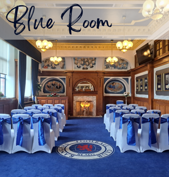 Wood panelled room with blue carpet and white chairs with blue ribbons set our theatre style with an isle running down the middle. Text reads Blue Room. 