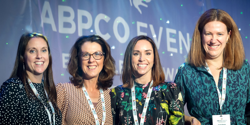 4 women looking at the camera, one holding and award