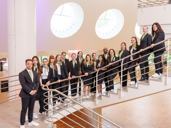 Professionally dressed people standing in a row down a flight of stairs