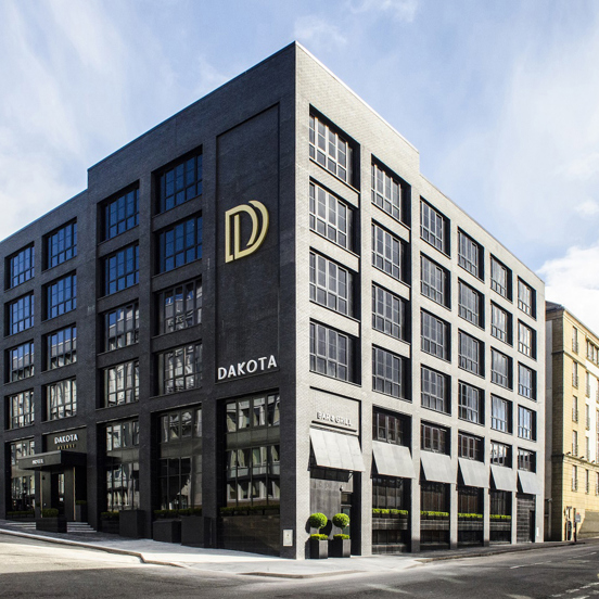Modern black hotel building with a large sign that read Dakota in large white lettering and DD initials in gold above.