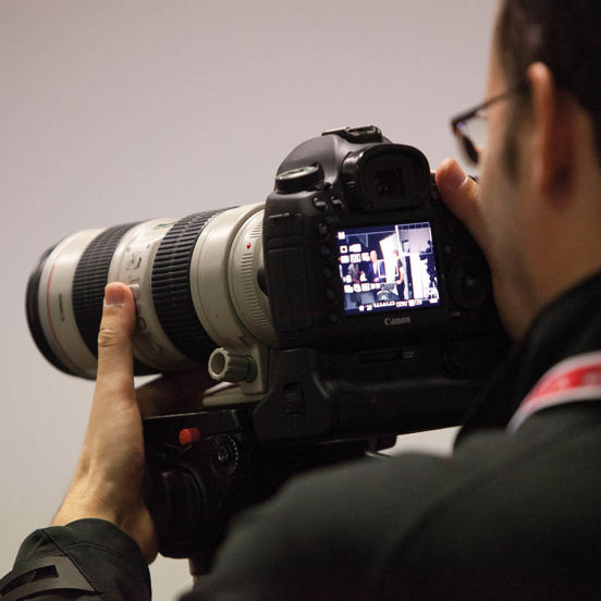 A man looking through the viewfinder of a professional camera