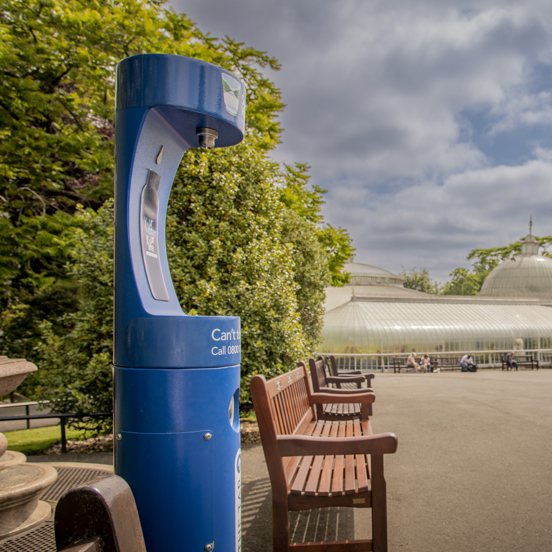 Blue water fountain in the Botanic Gardens with the Kibble Palace glass house in the background