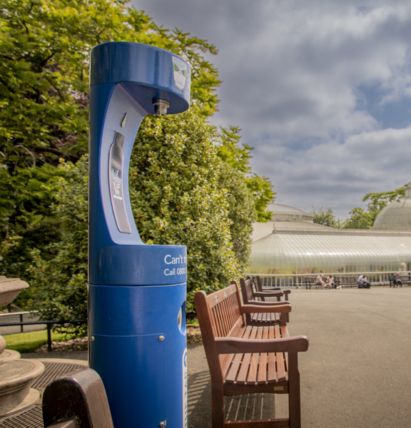 Blue water fountain in the Botanic Gardens with the Kibble Palace glass house in the background