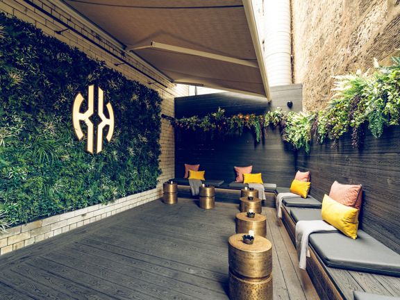 Open air terrace with banquette seating, living green wall and hanging greenery. 
