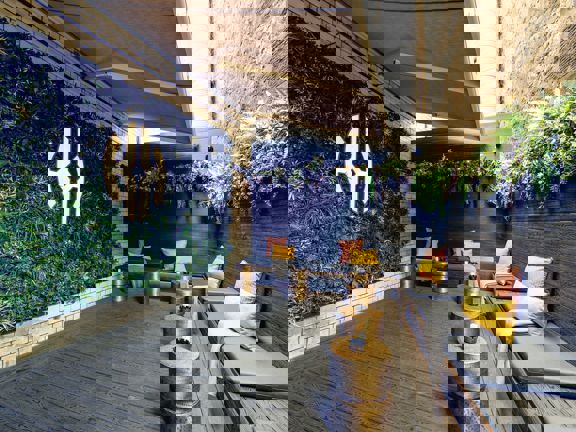 Open air terrace with banquette seating, living green wall and hanging greenery. 