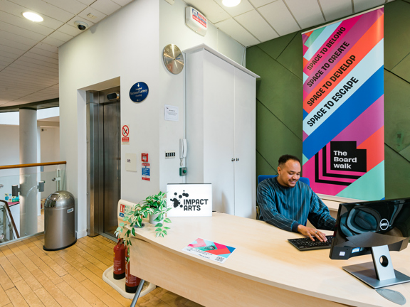 Man sits a desk at reception of The Boardwalk venue. 