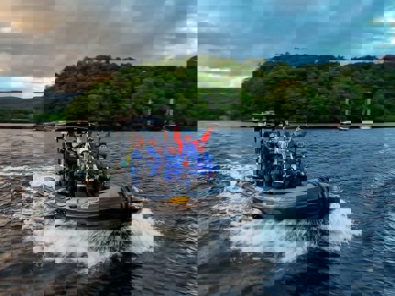 Speedboat on Loch Lomond with people waving at camera