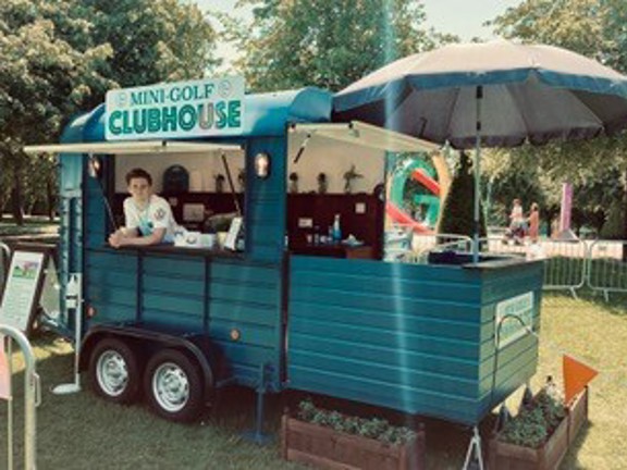 Mobile trailer designed as a mini golf clubhouse on a sunny day in park