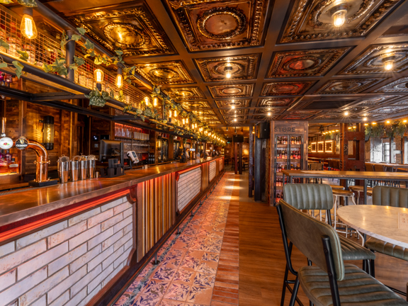 Modern eclectic bar called Wunderbar Glasgow West End - wooden and tiled flooring, tiled bar, marble tables, leather chairs and a row of lights across the top of the bar. 