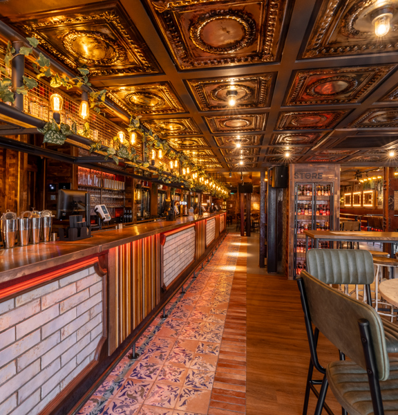 Modern eclectic bar called Wunderbar Glasgow West End - wooden and tiled flooring, tiled bar, marble tables, leather chairs and a row of lights across the top of the bar. 