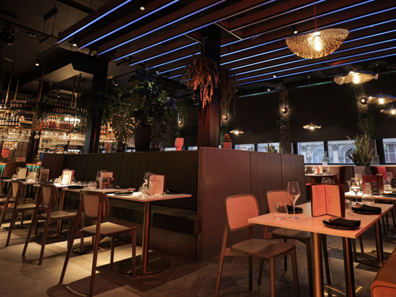 Restaurant with brightly coloured tables and chairs and blue neon lights across the ceiling. 