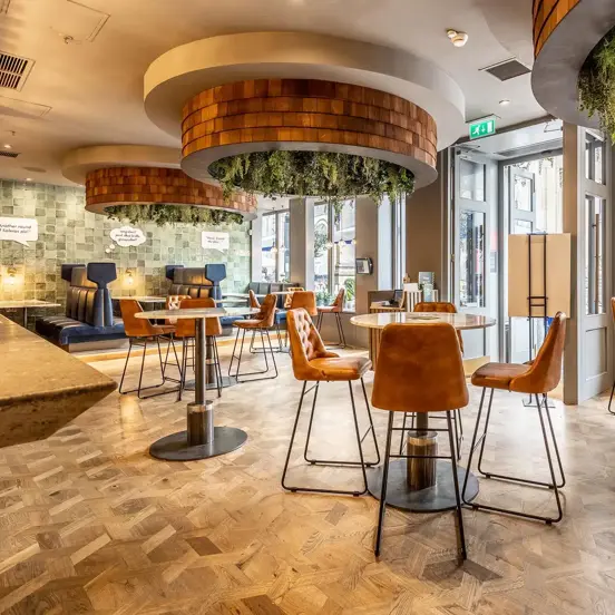 internal view of a restaurant with high tables in the middle and banquet seating on the sides.