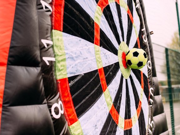 Football hitting the bullseye on a giant inflatable dartboard.