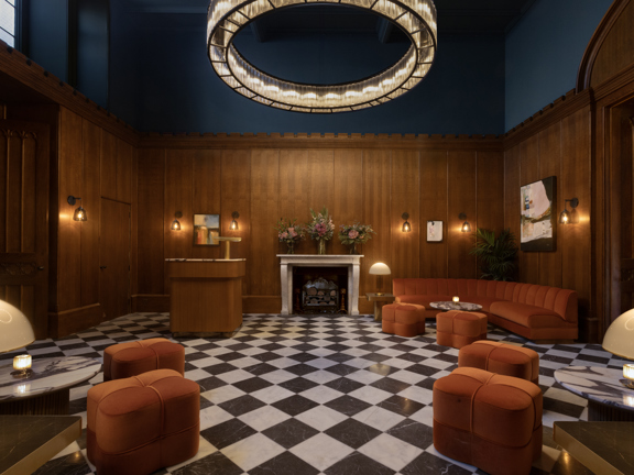 Mar Hall hotel reception with checkerboard flooring, rust velvet sofas, occasional seating, mental and glass lamps, wood clad walls and huge chandelier hanging from the ceiling