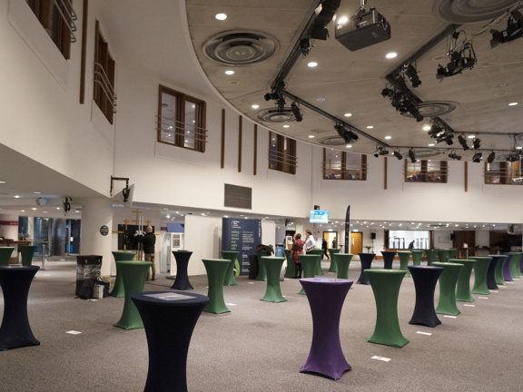 Conference room set up with rows of poser tables covered in black and green tablecloths. 
